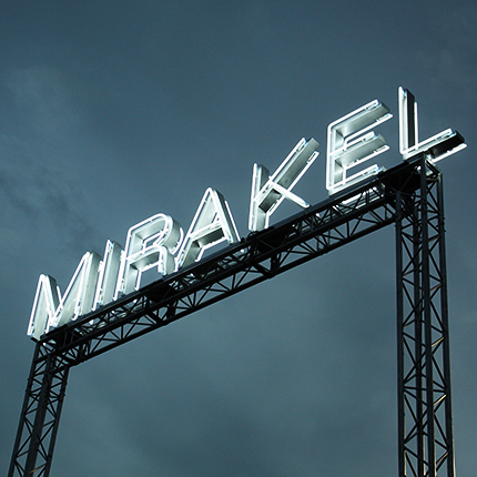 Mirakel Logo auf einem Dach bei Nacht aus Neonlicht