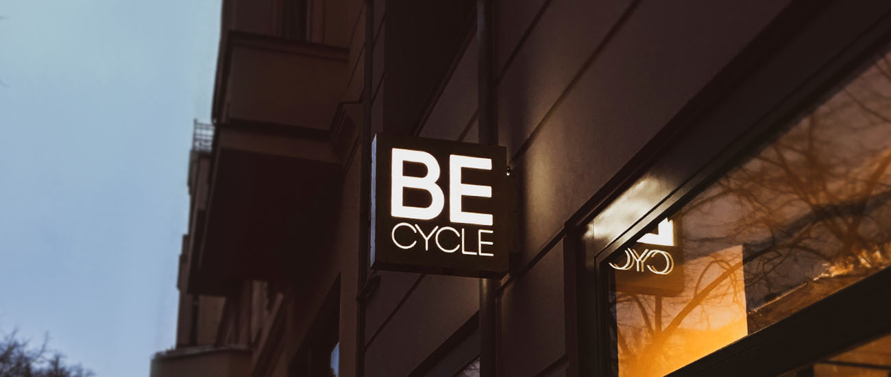 Becycle Berlin logo mounted as a nose-shield glowing at night on an exterior facade